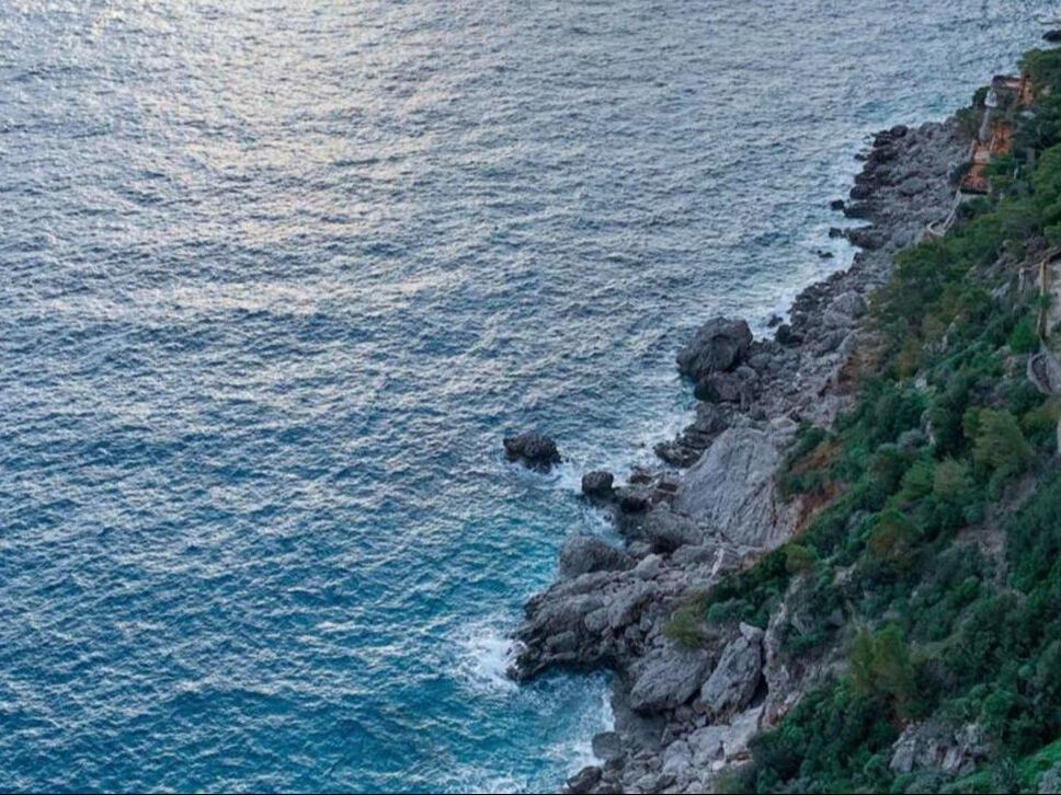 Rocky coastline and clear blue sea seen from above on a boat excursion in the Bay of Naples