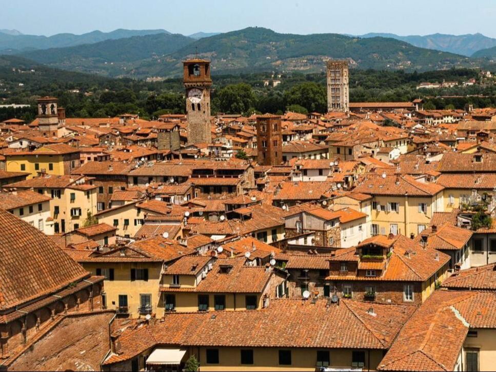 Medieval towers and terracotta rooftops of Lucca below the Apuan Alps
