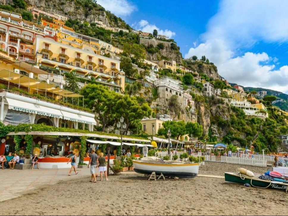 Positano beach promenade with colourful hotels and fishing boats