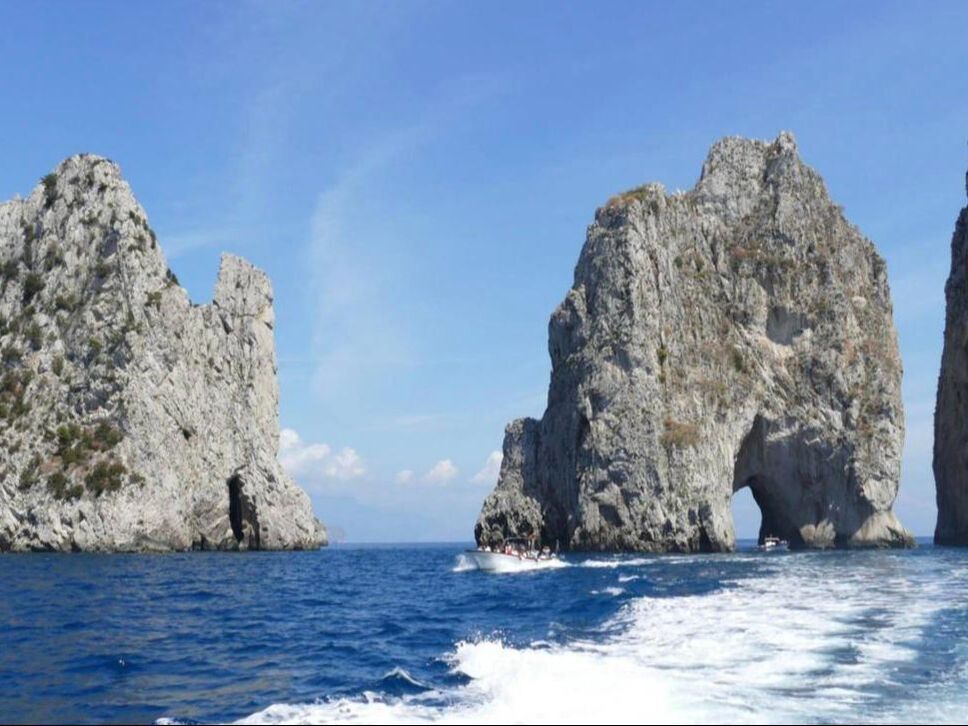Private boat sailing toward the Faraglioni rocks off Capri