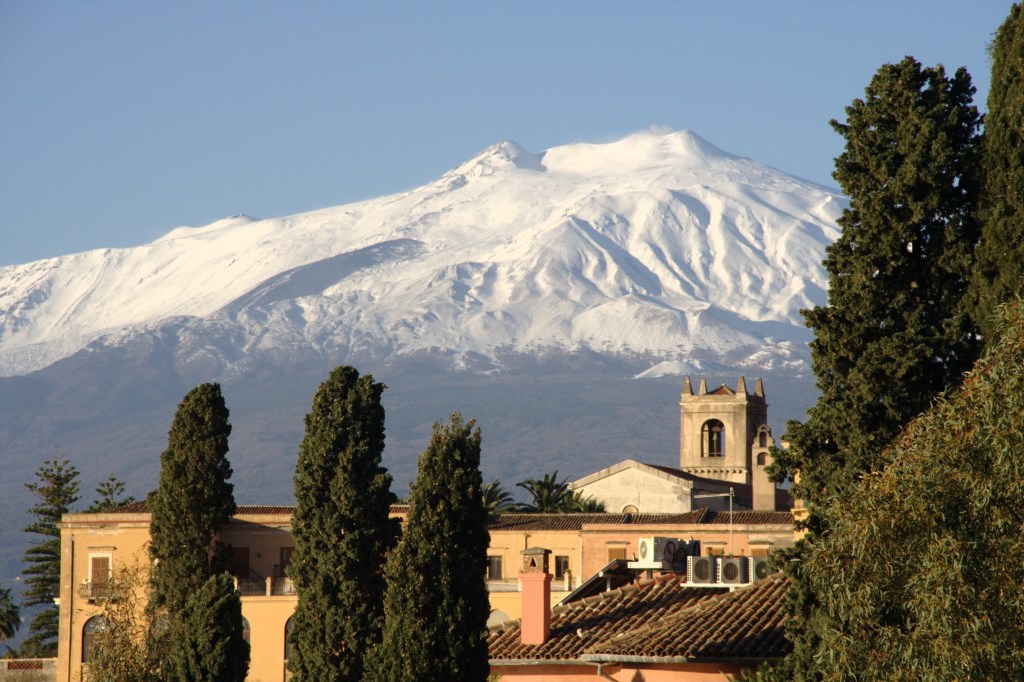 Snow-capped Mount Etna framed by cypress trees, Sicily